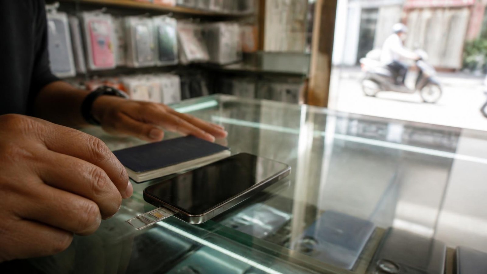 Buying a Cambodia SIM card: passport and phone with open SIM tray on a Phnom Penh phone-shop counter